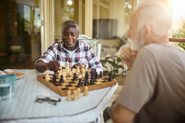 Two senior men enjoying a game of chess together outdoors